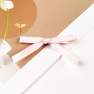 Detail showing soft pink satin ribbon bow hair clip with textured weave on elegant display