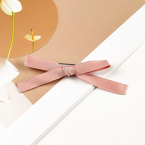 Close-up of pink ribbon bow hair clip with ribbed texture and metal duckbill clip back