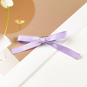 Detail of lavender satin bow hair clip with a smooth pearlescent texture and metal grip