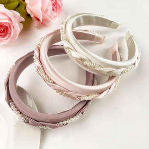 Detail of woven satin headbands with pearls in cream, pink, and mauve purple colors