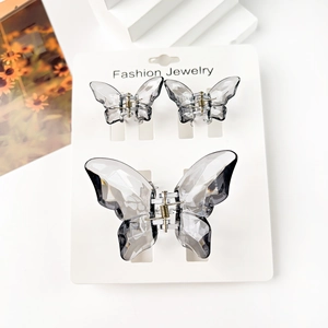 Three-piece set of translucent butterfly hair claws in smoky grey on a jewelry card