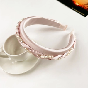 Detailed view of pink satin braided headband with pearls on white porcelain