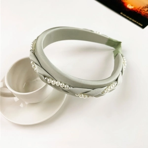 Detail of sage green braided headband with artificial pearls and silk fabric texture