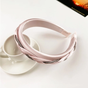 Detail of pink satin braided headband with sparkling rhinestone trim on a coffee cup