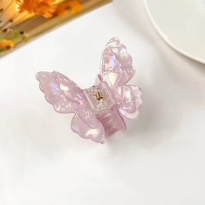 Detail shot of the iridescent pink butterfly hair claw clip with golden metal spring