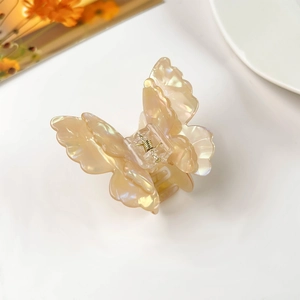 Detail view of pearlescent butterfly hair claw clip with golden metal spring and 3D design