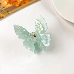 Macro shot of iridescent mint green butterfly hair claw with 3D resin wings and metal spring