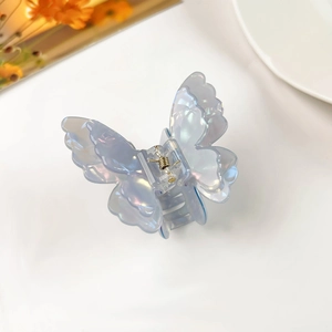 Detailed close-up of a pearlescent blue 3D butterfly hair claw clip on white background