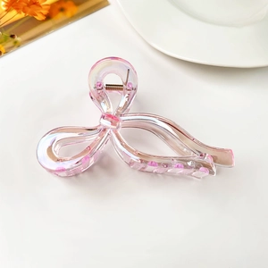 Detail of iridescent pink bow hair claw clip with transparent texture and metal spring