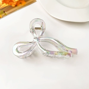 Detailed macro view of iridescent ribbon hair claw clip with golden metal spring