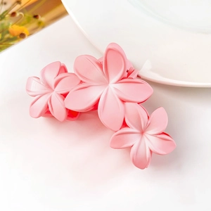 Dettaglio del fermaglio per capelli rosa opaco con tre eleganti motivi a 5 petali