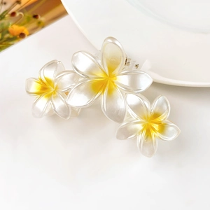Vista dettagliata di tre fermagli per capelli a plumeria bianca con sfumature gialle