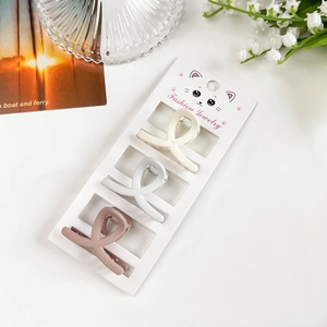 Trois mini pinces à cheveux mates en crème, gris et rose sur une carte de support