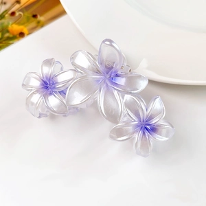 Dettaglio di una grande pinza per capelli viola traslucida con tre fiori di frangipane