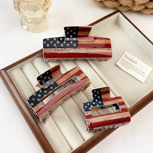 Three-piece American flag acrylic hair claw clips set displayed on brown velvet tray