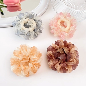 Detailansicht von vier Organza-Haargummis in Grau, Rosa, Orange und Braun mit Blumen-Look