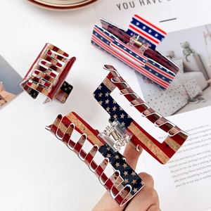 Detailed view of three large hair claws with American flag motifs and metal springs