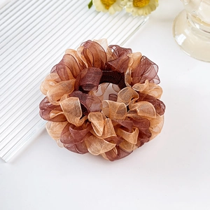 Detail von elegantem Organza-Haargummi mit braunen und goldenen Faltenlagen