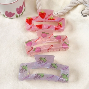 Detailed view of three large fruit hair claws in strawberry, peach and grape patterns