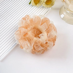 Detail eines cremefarbenen Organza-Camellia-Scrunchies mit Rüschen und elastischem Haarband