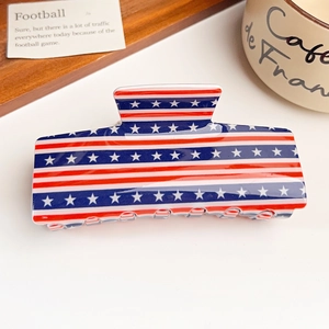Detail showing high-quality American flag acrylic hair claw clip on wooden tray