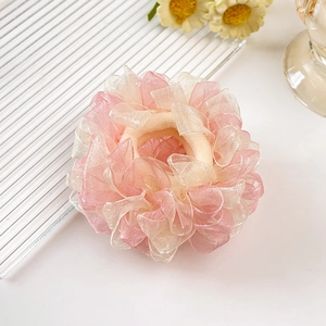Nahaufnahme der Textur des Camellia-Haargummis aus rosa und cremefarbenem Organza
