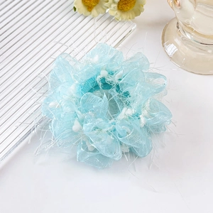 Detail eines hellblauen Organza-Haargummis auf Glastablett mit floralen Akzenten