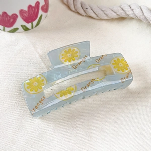 Detail of light blue semi-transparent fruit hair claw with pearlescent finish and oranges