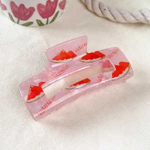 Detail of a large pink translucent hair claw with watermelon print and script text