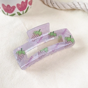 Detail of a large translucent purple acrylic hair claw clip with a grape print design