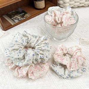 Détail de chouchous à fleurs en mousseline avec motifs roses et bleus sur nappe