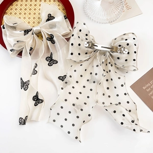 Elegant mesh bow hair clips with butterfly and polka dot prints on a wooden tray