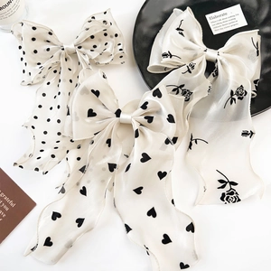 Close-up of three organza bow hair clips with polka dots, hearts, and rose patterns