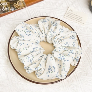Vue détaillée du chouchou blanc à motif floral bleu avec une texture de tissu doux