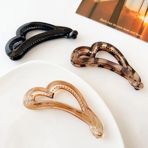 Three heart-shaped banana hair clips in black, leopard, and amber resin finishes