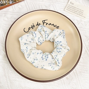 Vue détaillée du chouchou floral crème avec fleurs bleues sur une assiette en céramique