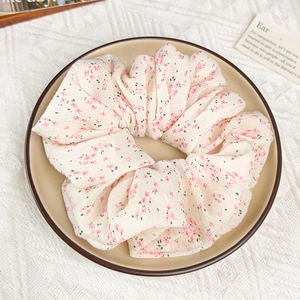 Détail d'un chouchou floral avec fleurs roses sur tissu beige dans un plat en céramique
