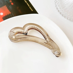 Detail view of a translucent amber heart-shaped hair clip on a white plate