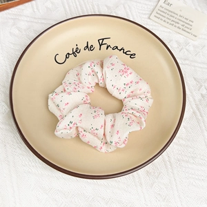 Détail d'un chouchou floral avec fleurs roses posé sur une assiette en céramique