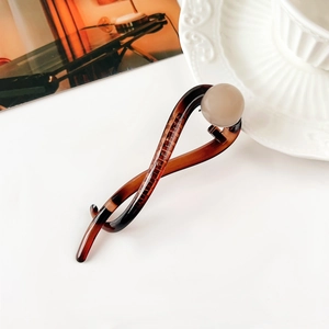Elegante fermaglio per capelli a tartaruga con perla beige su sfondo minimalista