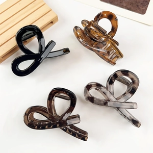 Detail view of four elegant bow hair claws in black, amber, and tortoiseshell patterns