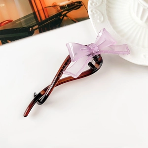 Dettaglio del fermaglio per capelli con fiocco viola traslucido e trama tartarugata