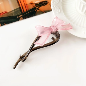 Dettaglio del fiocco rosa opaco e molletta a banana in resina caffè per coda di cavallo