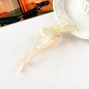 Dettaglio di un fermaglio per capelli a fiocco in resina giallo crema su piatto