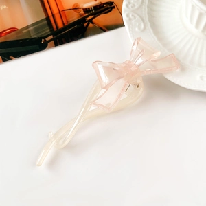 Dettaglio del fermaglio per capelli a fiocco in resina rosa su sfondo minimalista
