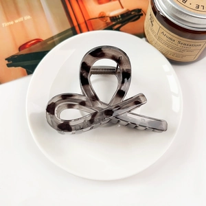 Detail of grey tortoiseshell hair claw clip with acetate texture on a white plate