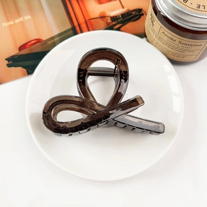 Macro shot of minimalist translucent coffee brown acrylic hair claw clip on a white plate