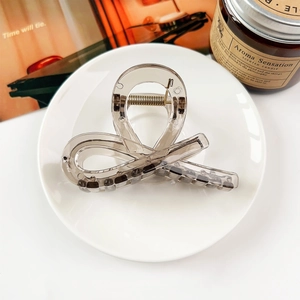 Close-up of a large minimalist amber-colored hair claw clip on a stylish white plate