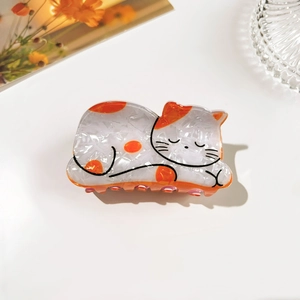 Close-up of cute white and orange cat shaped hair claw clip with glossy pearl finish