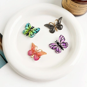 Gros plan sur des barrettes papillon dégradées avec textures fines sur plat blanc